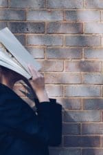 woman covering her face with white book